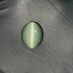 Green cat's eye gemstone on a dark fabric background