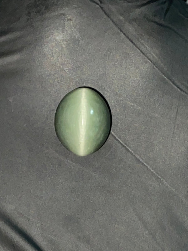 Green cat's eye gemstone on a dark fabric background
